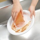 スコッチ・ブライト™ ハイブリッドネットスポンジを使って、皿についた油汚れを落とします。